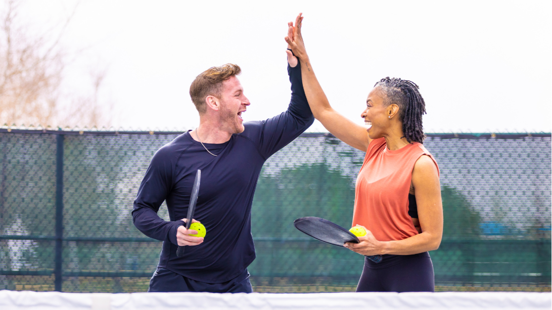 Man and woman high five playing pickleball