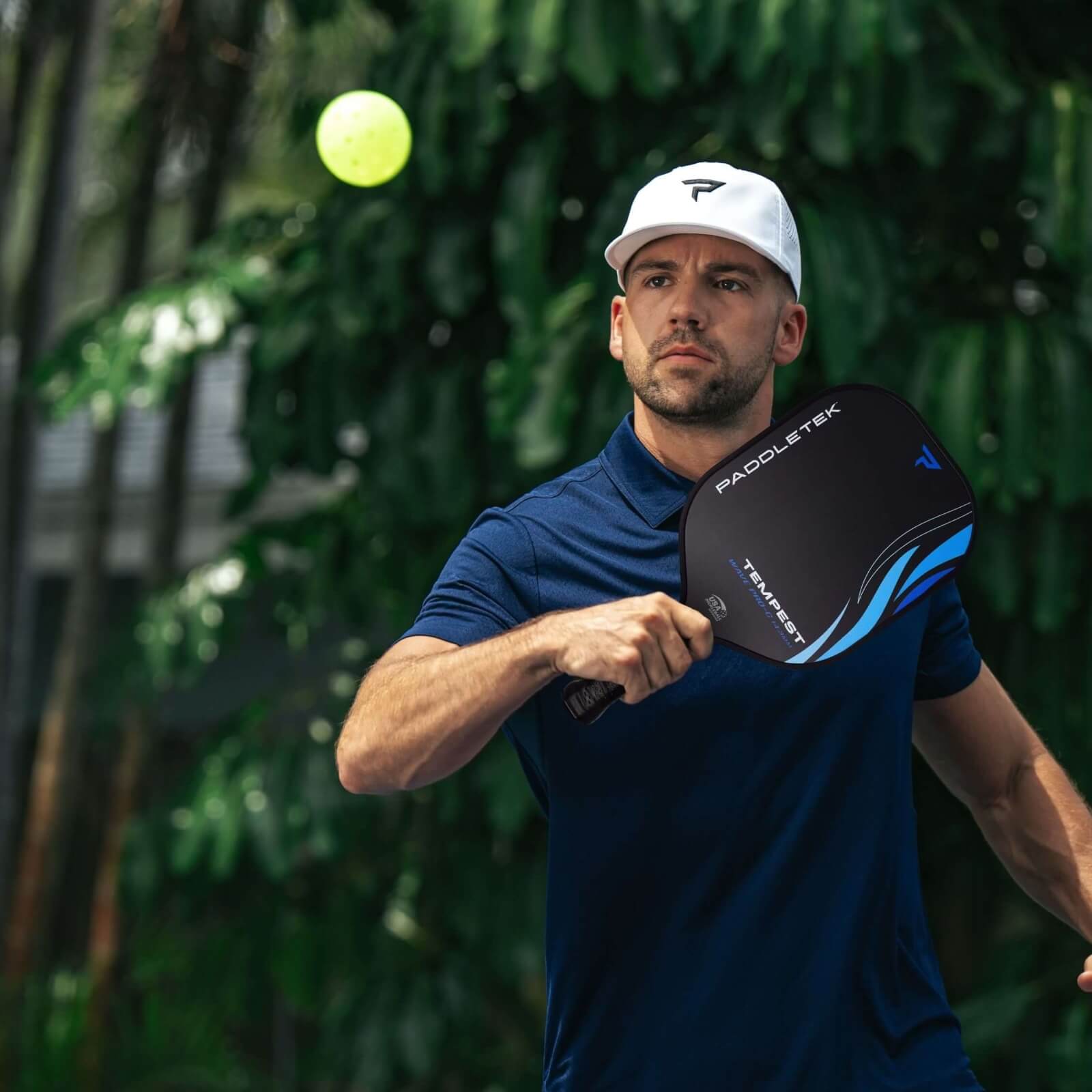 Man plays pickleball outdoors using Paddletek Tempest blue paddle